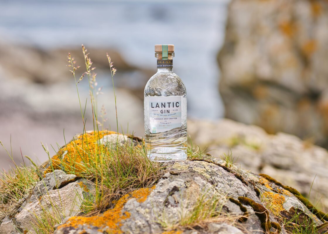 Glass gin bottle with label in Cornwall on rocks